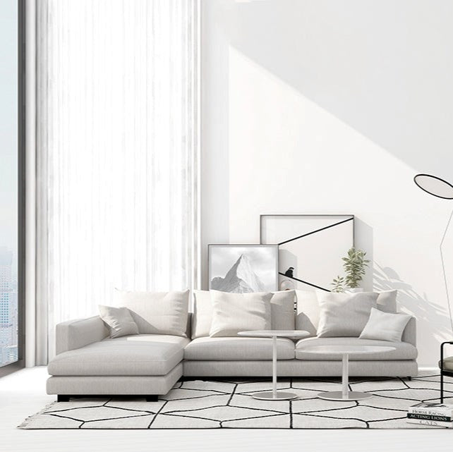 Modern living room with a white sectional sofa, abstract art, and a geometric rug.