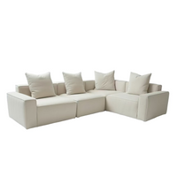 Beige sectional sofa with cushions in a modern room with large windows.