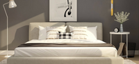 Nature bed in beige upholstery with grey bedding against a dark grey wall with art