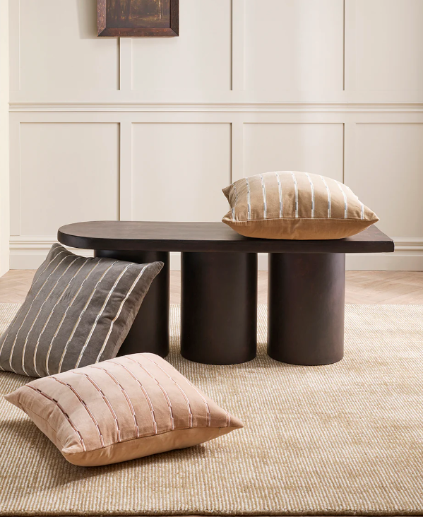 Corbett floor rug in a living room with dark round timber coffee tables and a cushion
