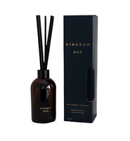 Kingdom silk fibre diffuser in a dark amber glass bottle with black reeds beside its navy box