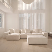 Elio Junior corner sofa and ottoman in cream fabric in a double-height room with a sheer ceiling pendant