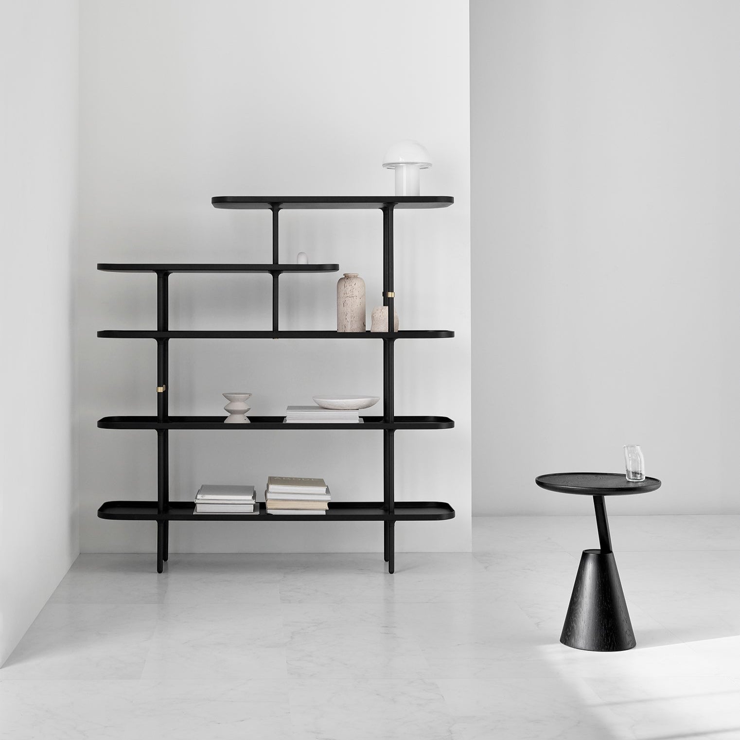 Mate side table in black beside a black open shelving unit in a bright white room